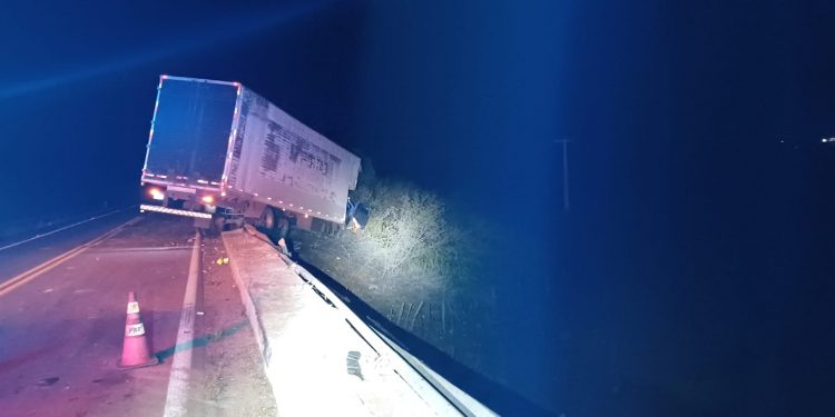 Caminhão fica pendurado em estrutura de ponte na BR-304